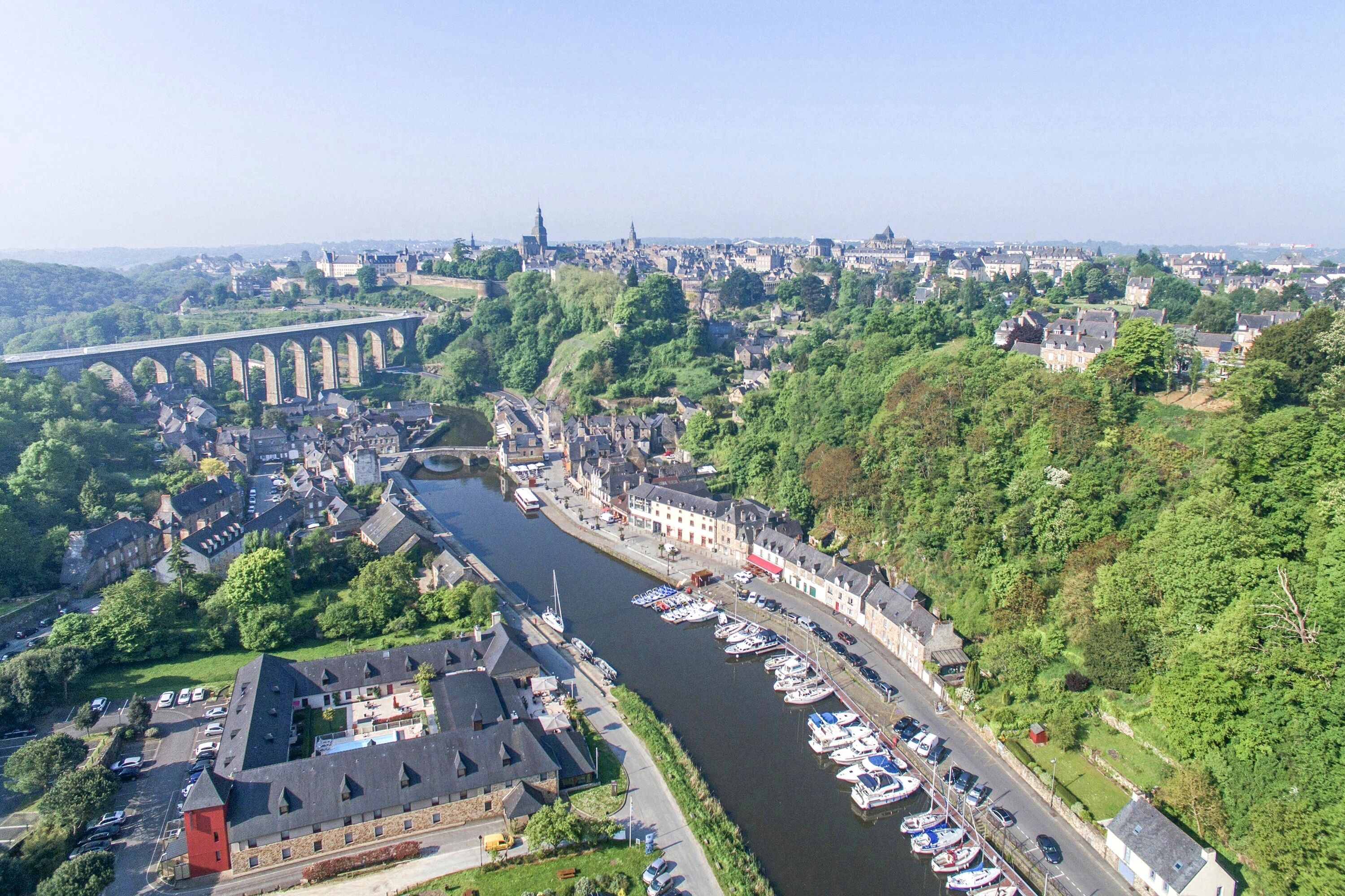 Ein Luftbild einer Flussstadt mit einer historischen Brücke, einem Yachthafen mit Booten und traditionellen Gebäuden.