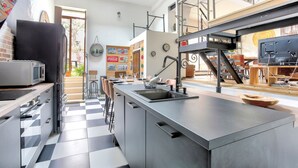 Une cuisine moderne dotée d’un grand îlot central, d’appareils électroménagers en acier inoxydable et d’un carrelage à motifs géométriques.