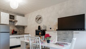 A modern kitchen with white cabinetry, a microwave, a coffee maker, and a flat-screen TV. - Kamélia - 10min des pistes (La Bresse)