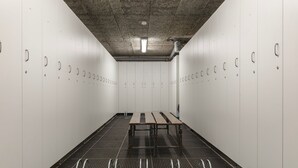 A row of lockers with a metal table in the center, a concrete ceiling, and a ventilation duct. - Kamélia - 10min des pistes (La Bresse)