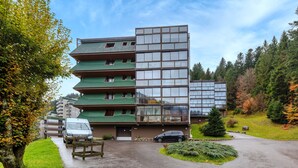 A multi-story building with a green roof and large windows, surrounded by trees and a parking area. - Kamélia - 10min des pistes (La Bresse)