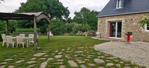 A stone house with a covered patio, a stone wall, and a gravel area. - La Maison Vert-Émeraude - Proche sentier randonnée (Férel)