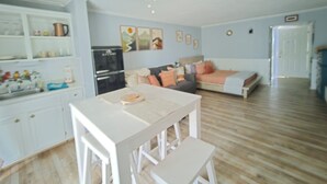 A compact living space with a kitchenette, a dining area, a sofa, and a ceiling fan. - Lake Escape Getaway (Fairfield Bay)