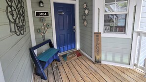A wooden porch with a blue door, a bench, and a welcome sign. - Lake Escape Getaway (Fairfield Bay)