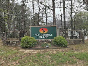 A sign for Summerhill Place with a stone wall and metal gate.