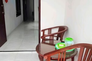 Un rincón de una habitación con una silla de madera y una mesa, una puerta y un pasillo.
