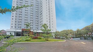 A modern multi-story hotel with a central courtyard, surrounded by greenery and a parking area.