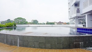 A swimming pool with a tiled edge, surrounded by a wooden deck.