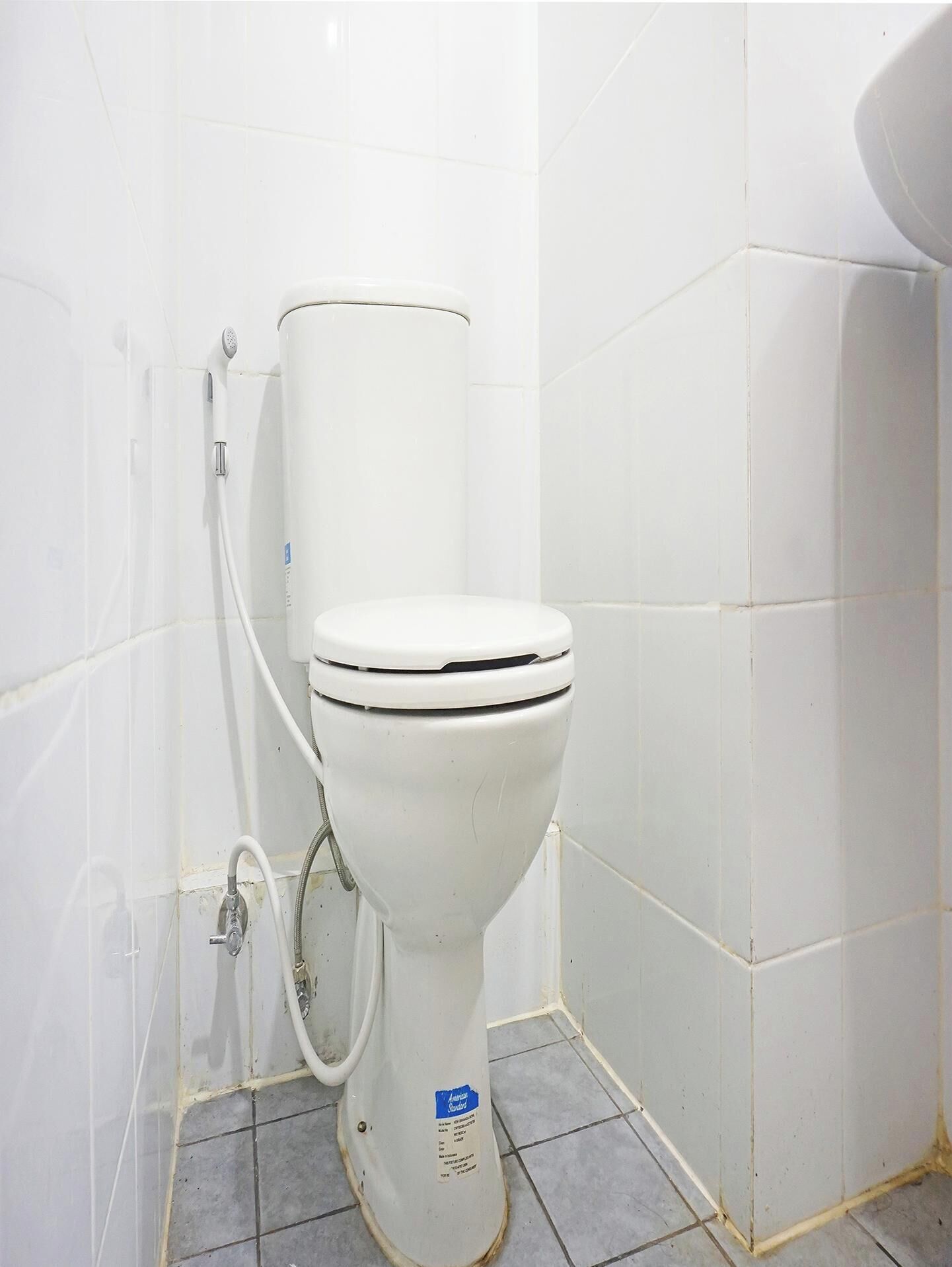 A white toilet in a bathroom with white tiled walls and floor.