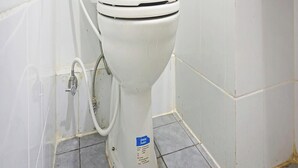 A white toilet in a bathroom with white tiled walls and floor.