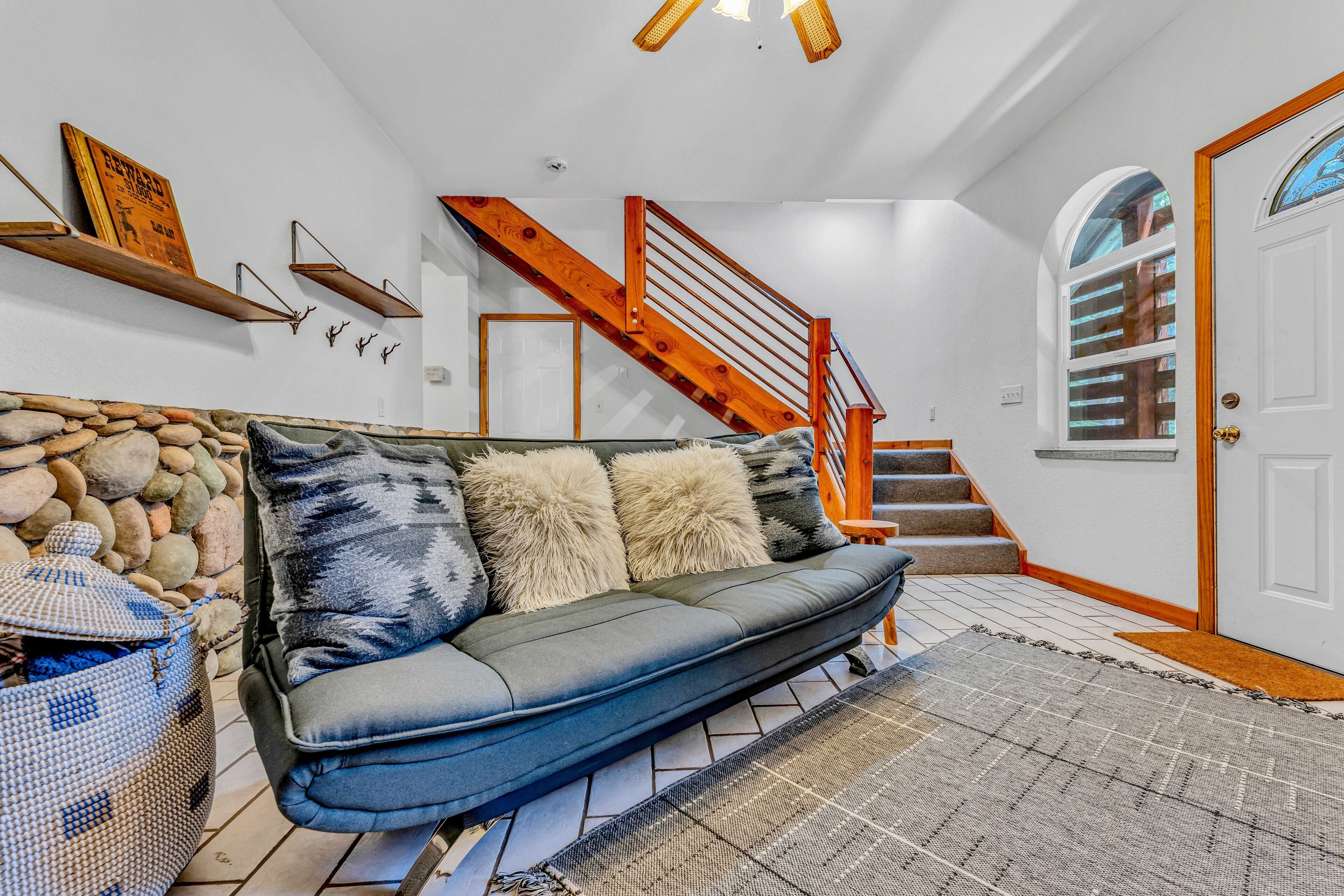 A living room with a sofa, a stone wall, a staircase, and a door.