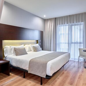 A modern hotel room with a large bed, a bedside table, a chair, and a window with curtains. - Hotel Turia Granada (Granada)