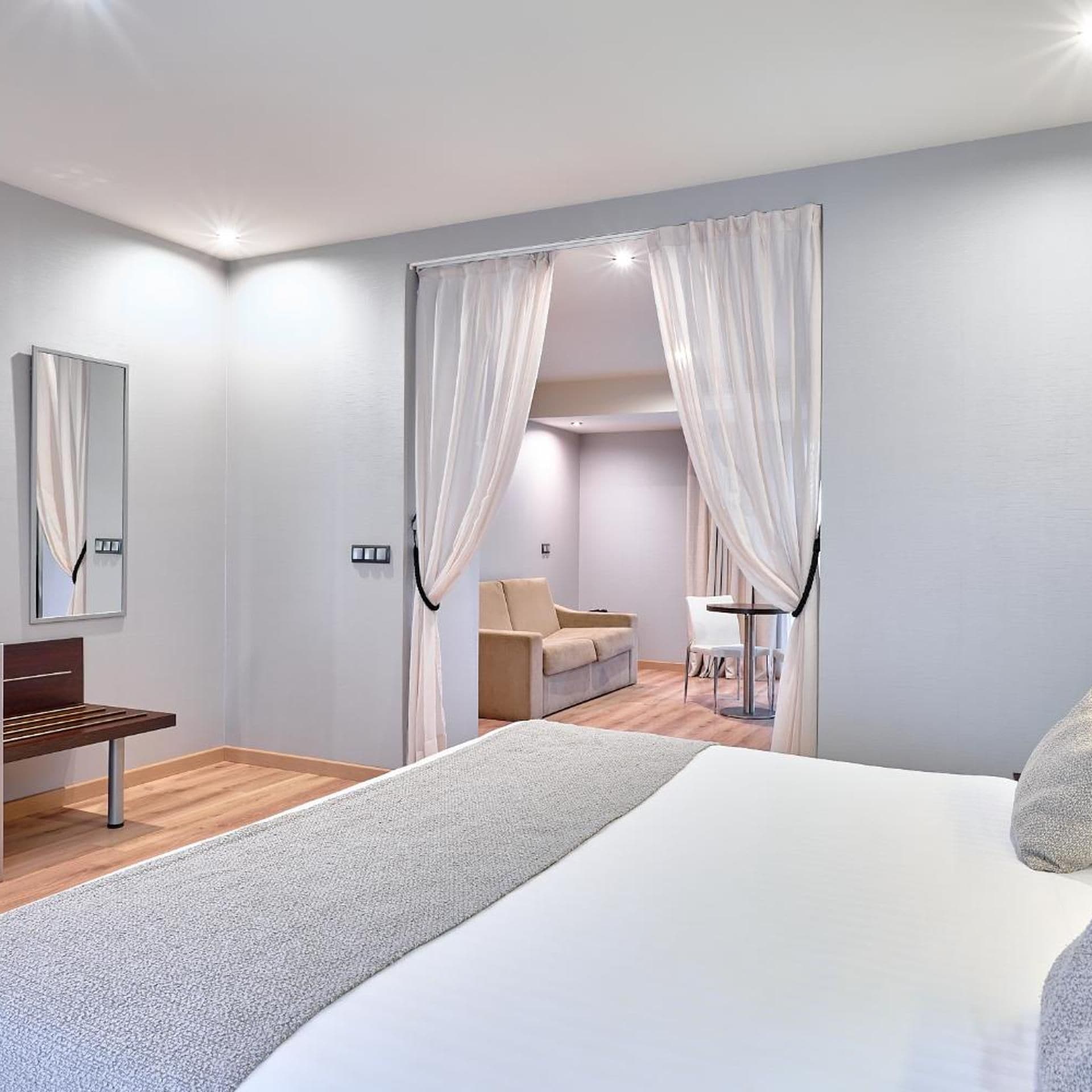 A bedroom with a bed, a desk, a chair, a sofa, and a table.