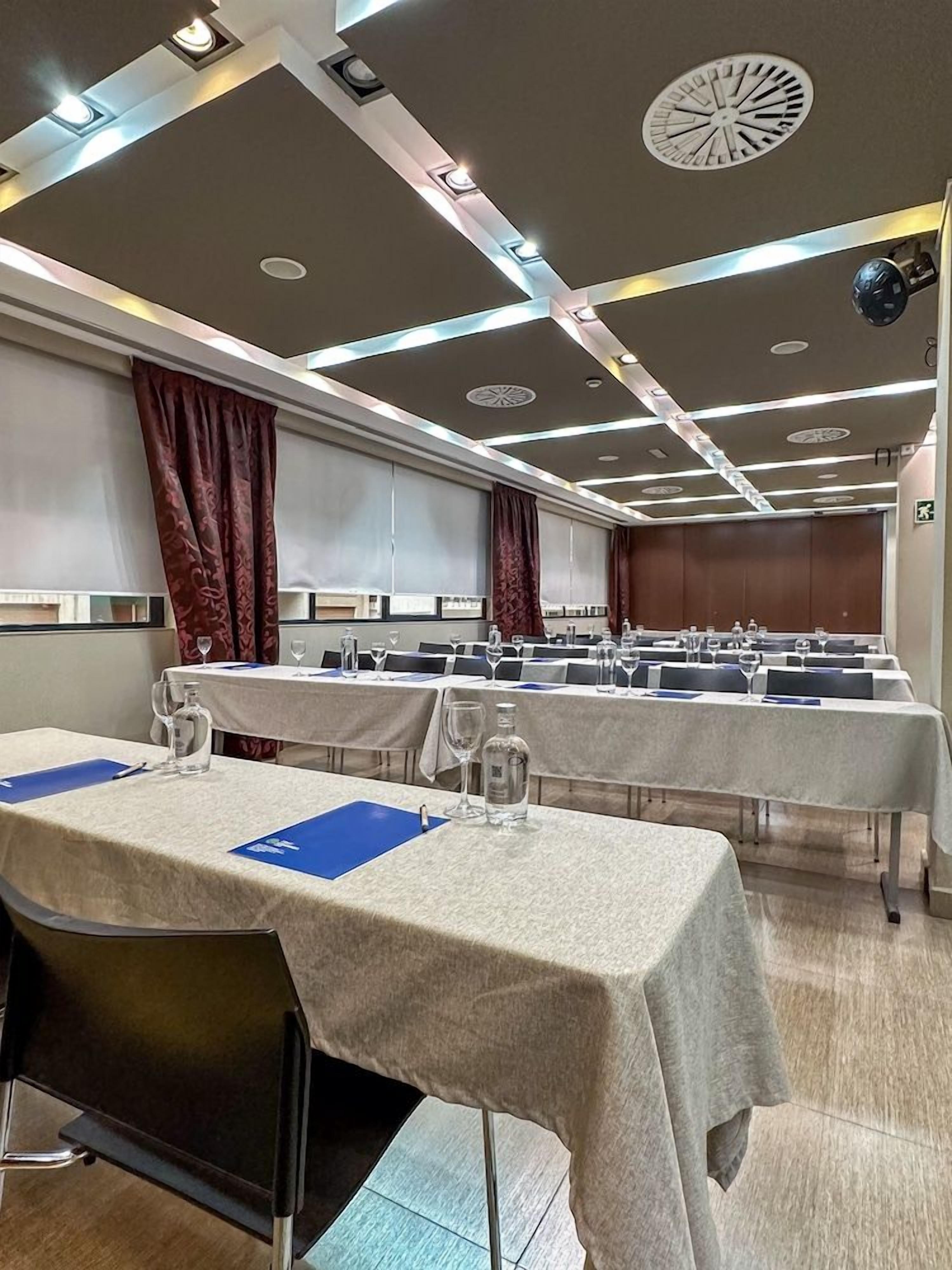 A conference room with tables set for meetings, equipped with chairs, water bottles, and nameplates.