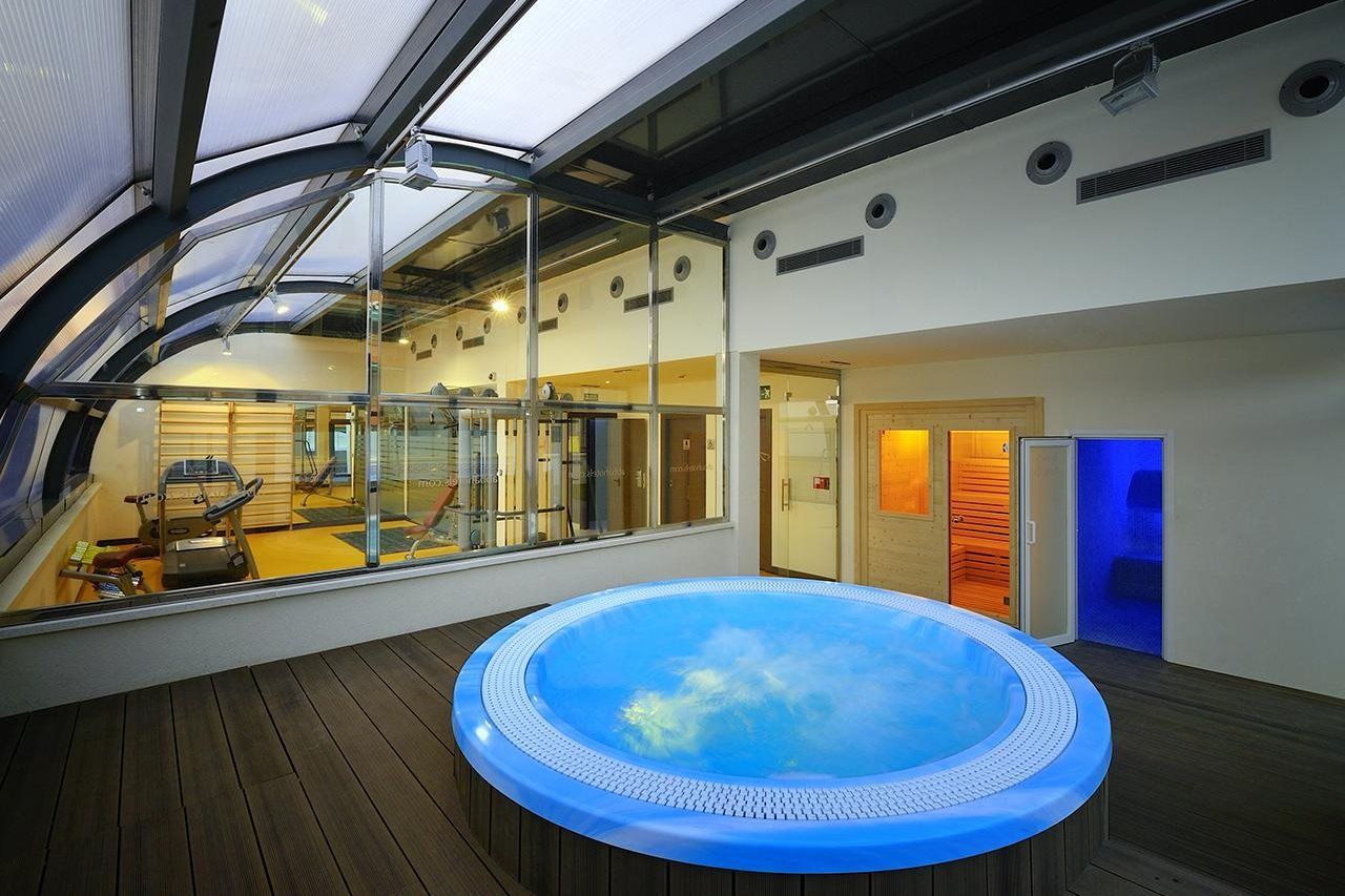 Un jacuzzi en una terraza de madera, con equipo de ejercicio al fondo.