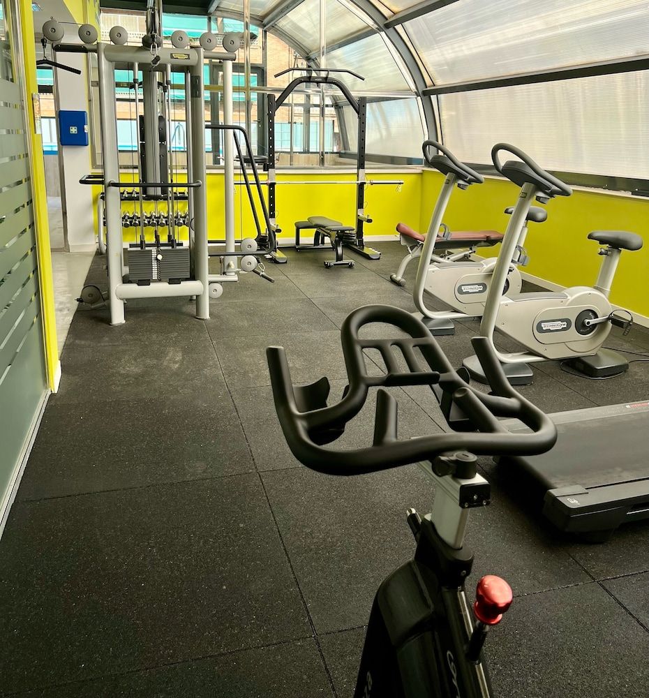Ein Fitnessstudio mit Trainingsgeräten, darunter Laufbänder und Kraftgeräte, unter einer Glaskuppel.