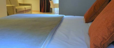 A hotel room with a bed, a chair, and a lamp.