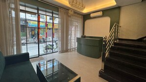 A hotel lobby with a reception desk, a staircase, and a seating area with a glass coffee table. - Hotel Aryan Inn (Haridwar)