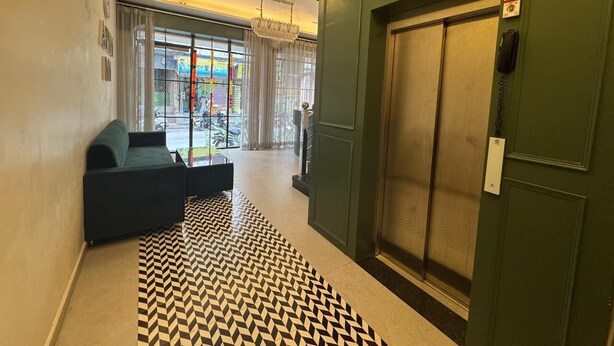 A lobby with a green elevator, a black and white patterned rug, and a green sofa. - Hotel Aryan Inn (Haridwar)
