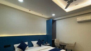A modern hotel room with a large bed, a desk, and a ceiling fan. - Hotel Aryan Inn (Haridwar)