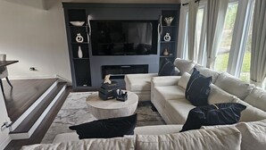 A modern living room with a sofa set, a coffee table, and a flat-screen TV mounted on a wall. - Family-Friendly Home with Style & Space (Chicago)