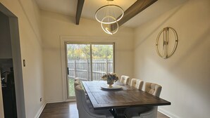 A dining area with a wooden table and six chairs, a vase with flowers, and a modern light fixture. - Family-Friendly Home with Style & Space (Chicago)