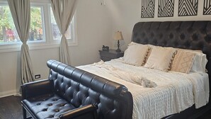 A bedroom with a large bed, a leather sofa, a ceiling fan, and decorative wall art. - Family-Friendly Home with Style & Space (Chicago)
