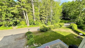 A deck with outdoor furniture, a mailbox, and a view of a road and surrounding greenery.