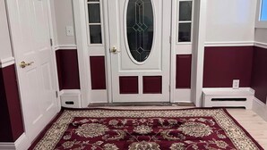A room with a white door with glass panels, a red carpet, and a small white step.