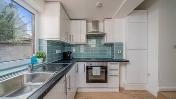 A modern kitchen with white cabinets, a stainless steel sink, and a built-in oven.