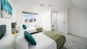 Un dormitorio con dos camas, una ventana, una puerta y un cuadro en la pared.