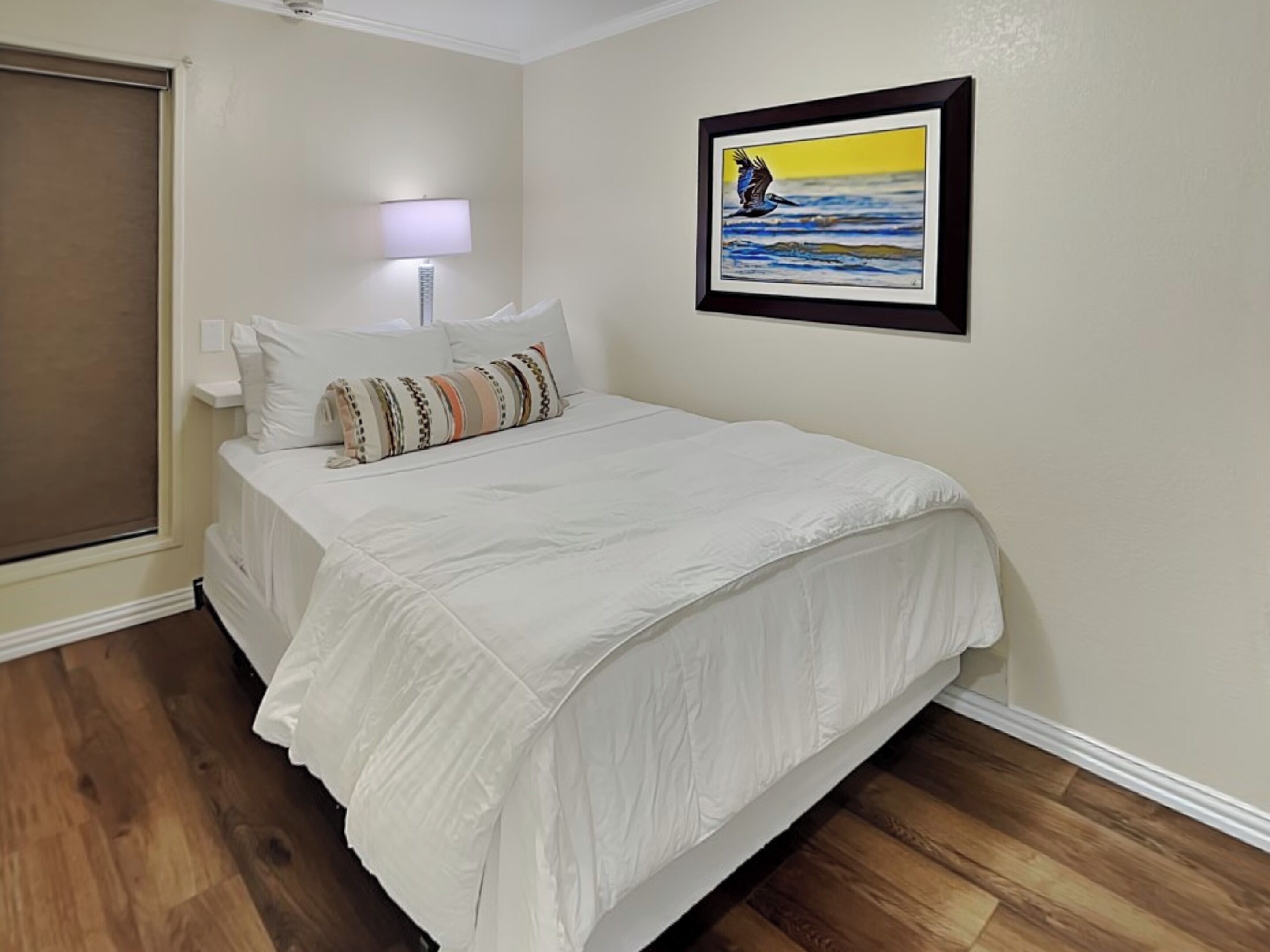 A bedroom with a bed, a nightstand, a lamp, and a framed picture on the wall.