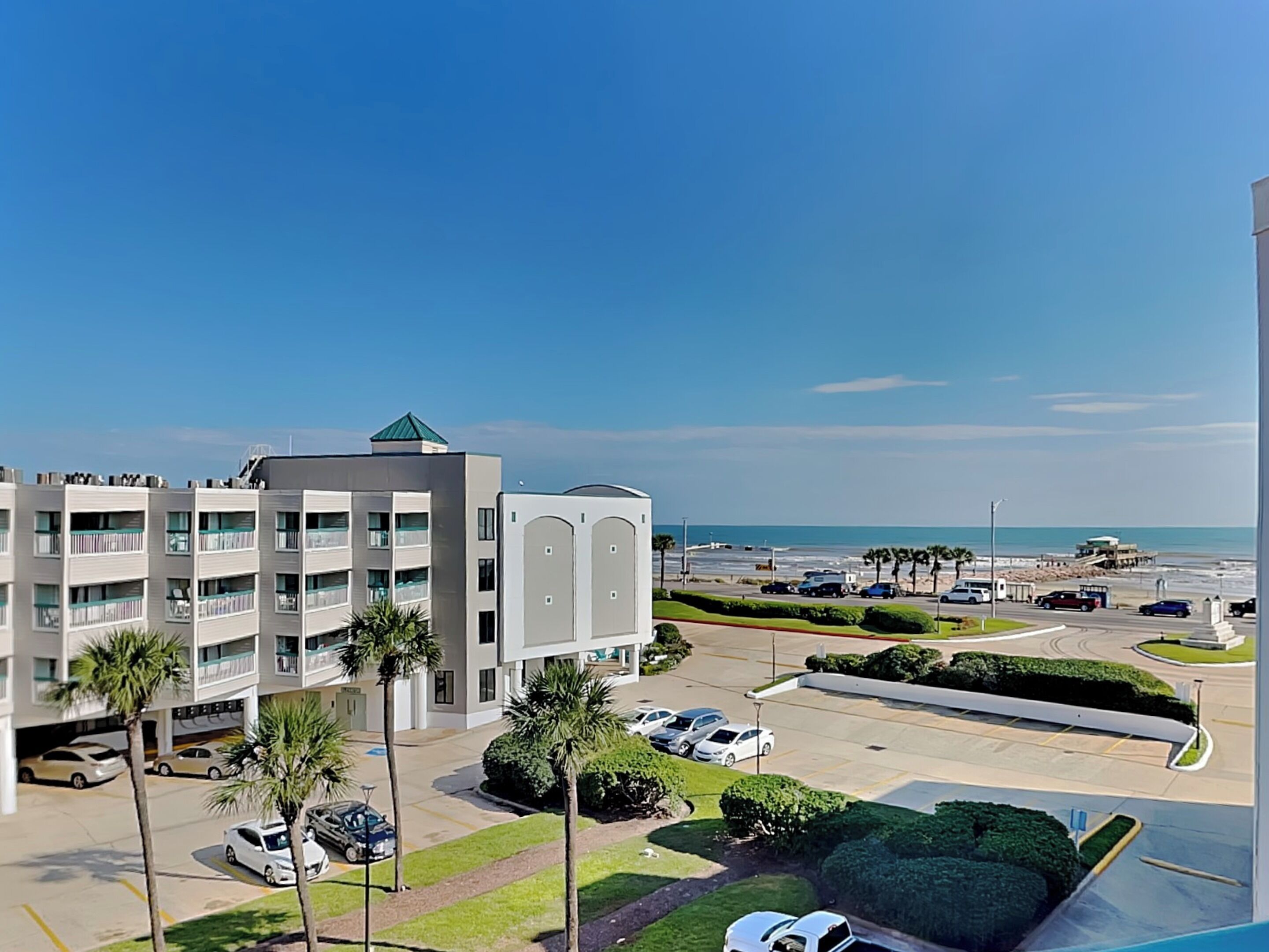Un hotel moderno con varios pisos, estacionamiento y vista a la playa.