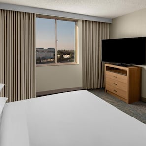A hotel room with a large bed, a television on a wooden stand, and a window with curtains. - Delta Hotels Santa Clara Silicon Valley (Santa Clara)