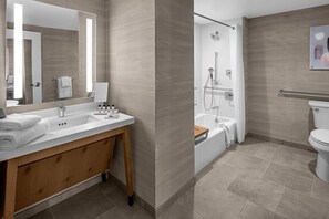 A modern bathroom with a large mirror, a sink, a wooden vanity, a shower, and a toilet. - Delta Hotels Santa Clara Silicon Valley (Santa Clara)