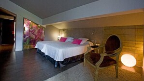 A bedroom with a bed, a chair, a wall with a light, and a door. - Castillo Hotel (Olaberria)