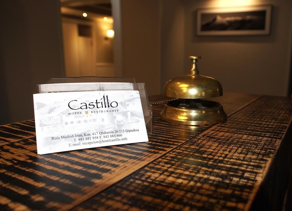 Een hotel receptiebalie met een bordje voor 'Castillo Hotel Restaurante' en een koperen bel.