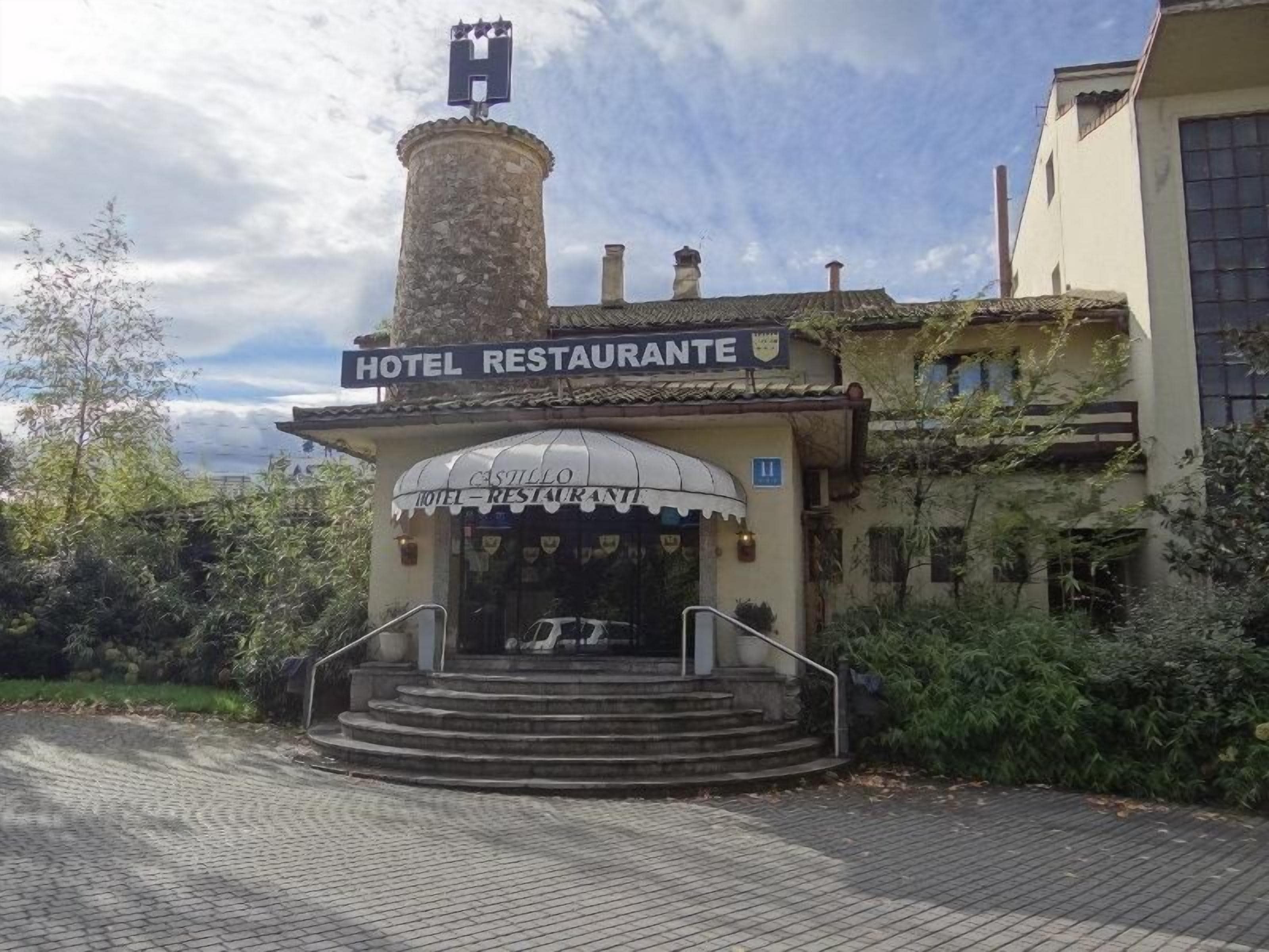 Een hotel ingang met een bord waarop 'HOTEL RESTAURANTE' staat en een trap die naar de deur leidt.