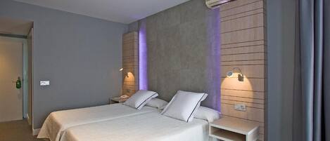 A hotel room with two beds, a built-in shelf, an air conditioning unit, and a door.