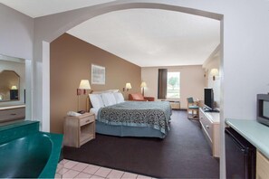 A hotel room with a bed, desk, chair, TV, and a bathroom with a bathtub. - Quality Inn & Suites Decatur - Priceville I-65 (Decatur)