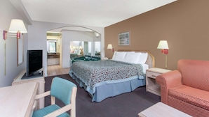 A hotel room with a bed, a desk with a computer, a TV, a chair, and a sofa. - Quality Inn & Suites Decatur - Priceville I-65 (Decatur)