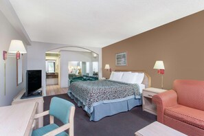 A hotel room with a bed, a desk with a computer, a TV, a chair, and a sofa. - Quality Inn & Suites Decatur - Priceville I-65 (Decatur)