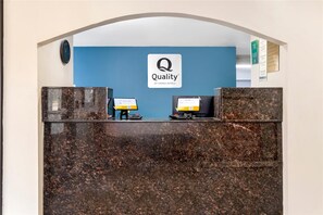 A hotel reception desk with a blue wall and a sign that reads 'Quality by Choice Hotels.' - Quality Inn & Suites Decatur - Priceville I-65 (Decatur)