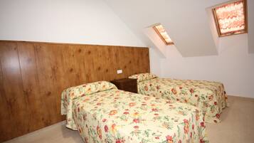 Una habitación con dos camas, cabecero de madera y un tragaluz.