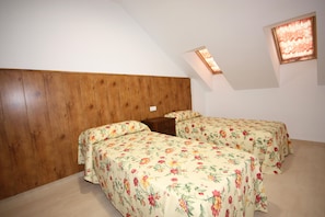 Une chambre avec deux lits, une tête de lit en bois et un puits de lumière.