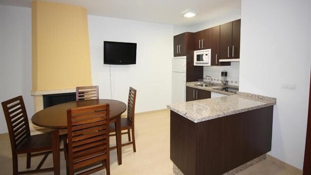 A compact kitchen with dark cabinets, a microwave, and a granite countertop. - Campillo Apartamentos Rurales (La Iruela)