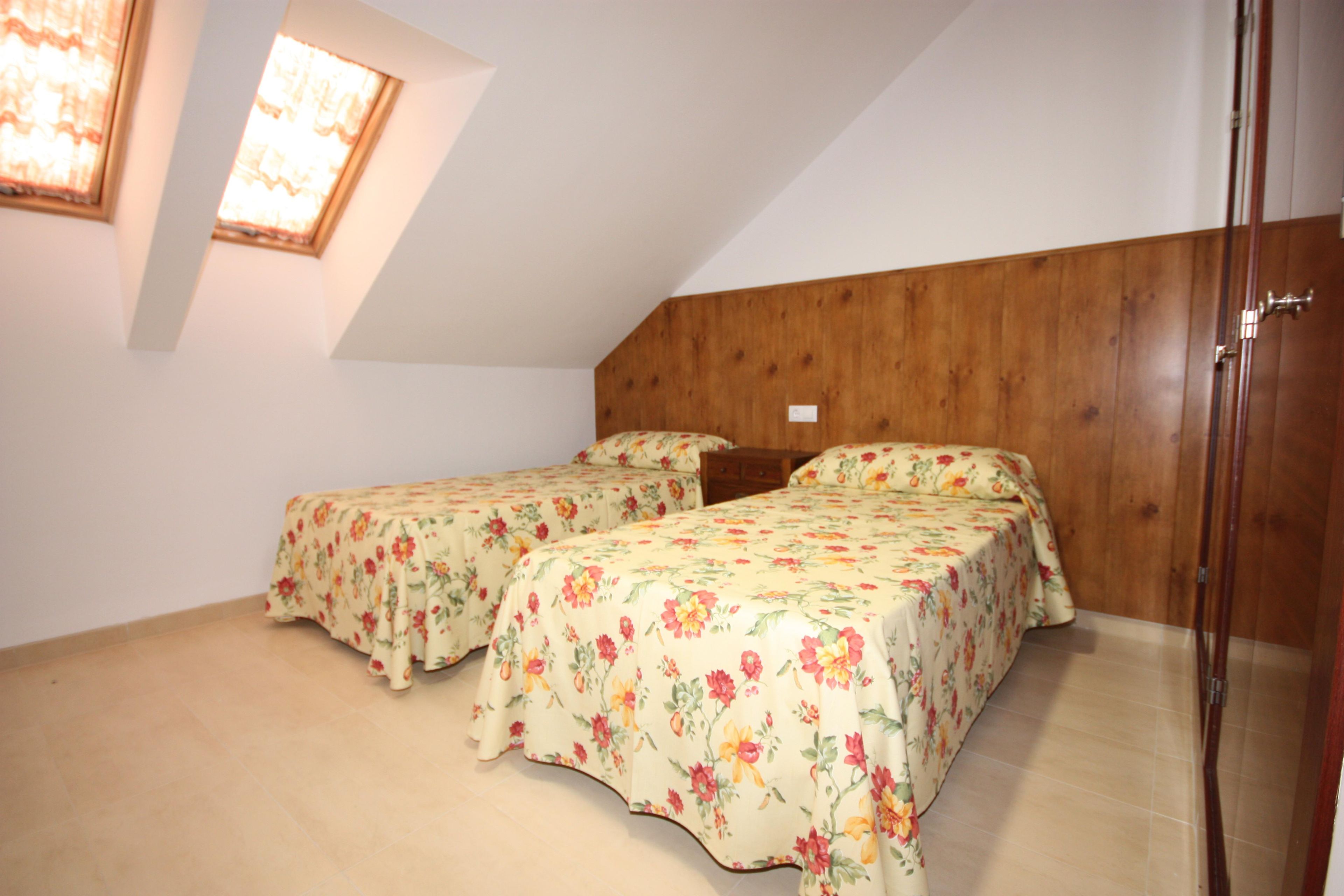 Un dormitorio con dos camas, cabeceros de madera y un tragaluz.
