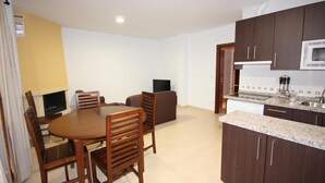 A compact kitchen with dark wooden cabinets, a microwave, and a granite countertop. - Campillo Apartamentos Rurales (La Iruela)