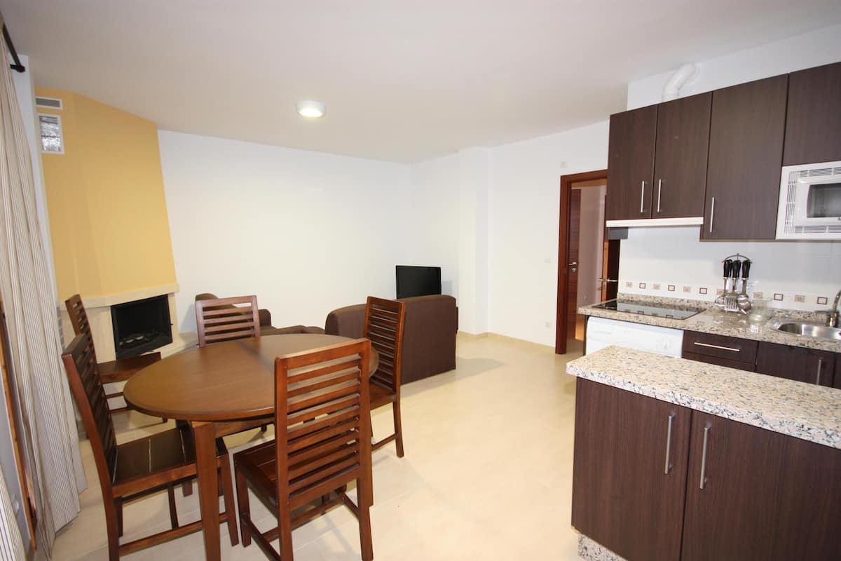A compact kitchen with dark wooden cabinets, a microwave, and a granite countertop.