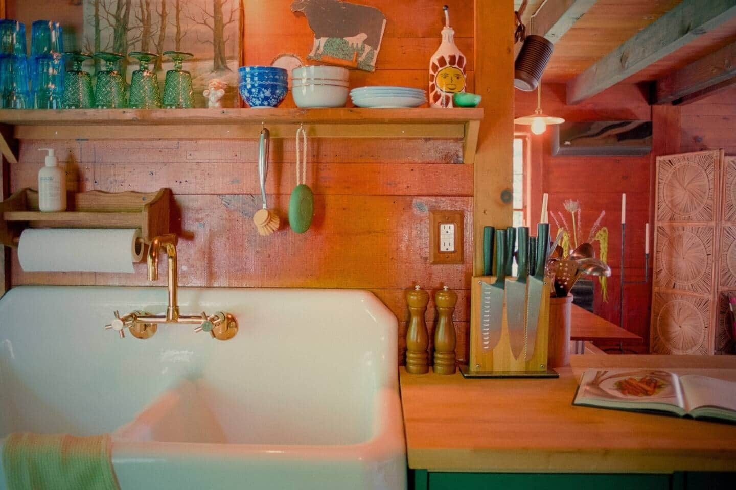 Ein rustikales Badezimmer mit einer großen Badewanne, Holzregalen mit verschiedenen Pflegeprodukten und einer Holzwand mit dekorativer Verkleidung.